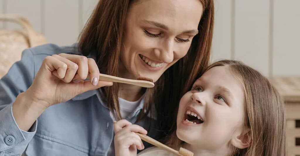 A mother and daughter enjoying quality time while brushing their teeth together indoors.