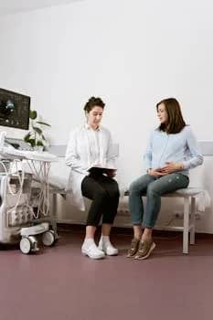 A pregnant woman consults with a doctor in a medical clinic, discussing health care and maternity.