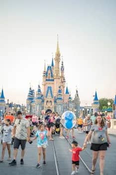 Tourists and families exploring a famous theme park with a castle landmark.