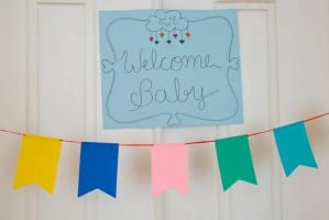 Cheerful baby shower decorations with colorful banner and welcome sign displayed indoors.