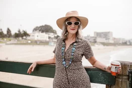 Confident senior woman in stylish attire enjoys a relaxed day at the beach.