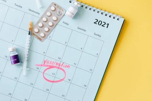 Calendar with vaccination date circled alongside vaccine vials and syringe for COVID-19 prevention.