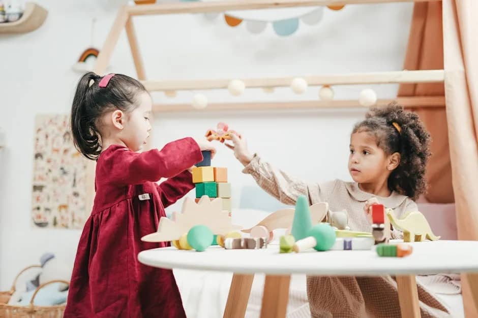 Two young girls enjoying playtime with wooden toys indoors in a warm, colorful playroom.