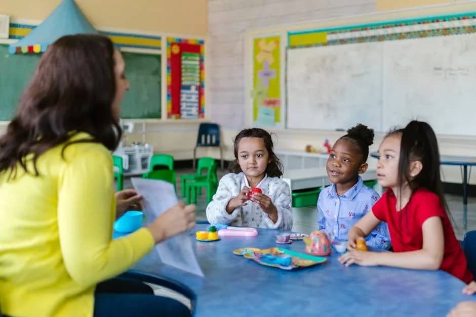 Three diverse young girls engage with a teacher in a vibrant classroom environment.