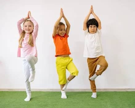 Three diverse children practicing yoga indoors, showcasing joy and balance.