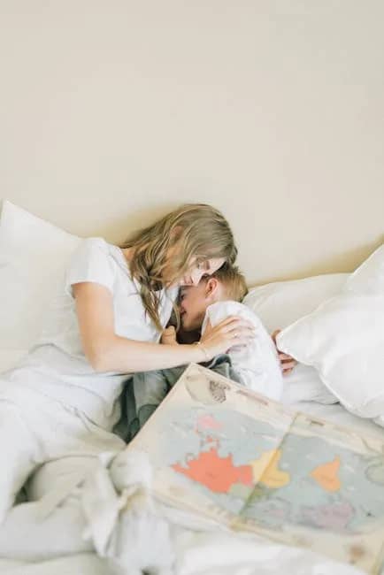 A mother and son enjoy quality time together, relaxing on the bed with a map.