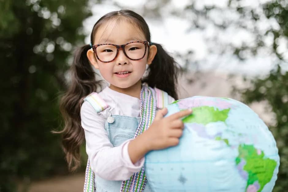 Cute child holding a globe in the park, exploring the world.