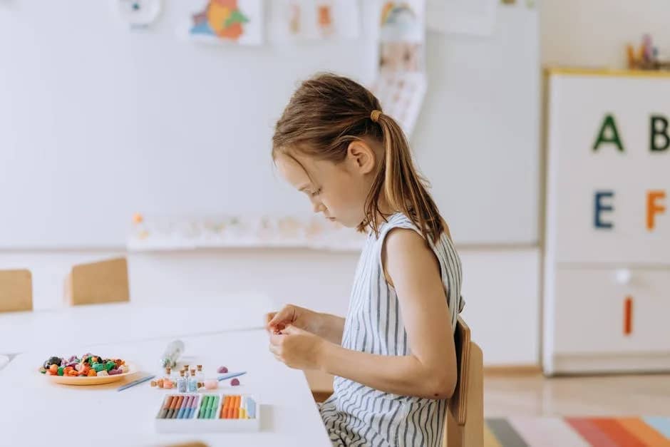 A young girl crafting with colored pencils in a bright, creative classroom setting.