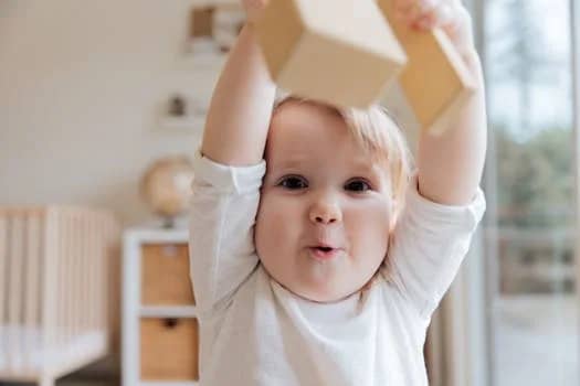 Adorable baby enjoying playtime with wooden blocks in a cozy indoor setting. Perfect depiction of joy and learning.